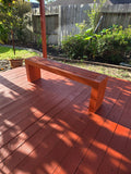 Red-stained slatted wooden bench on a matching red deck