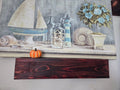 Dark-stained solid wood floating shelf mounted on a wall under artwork