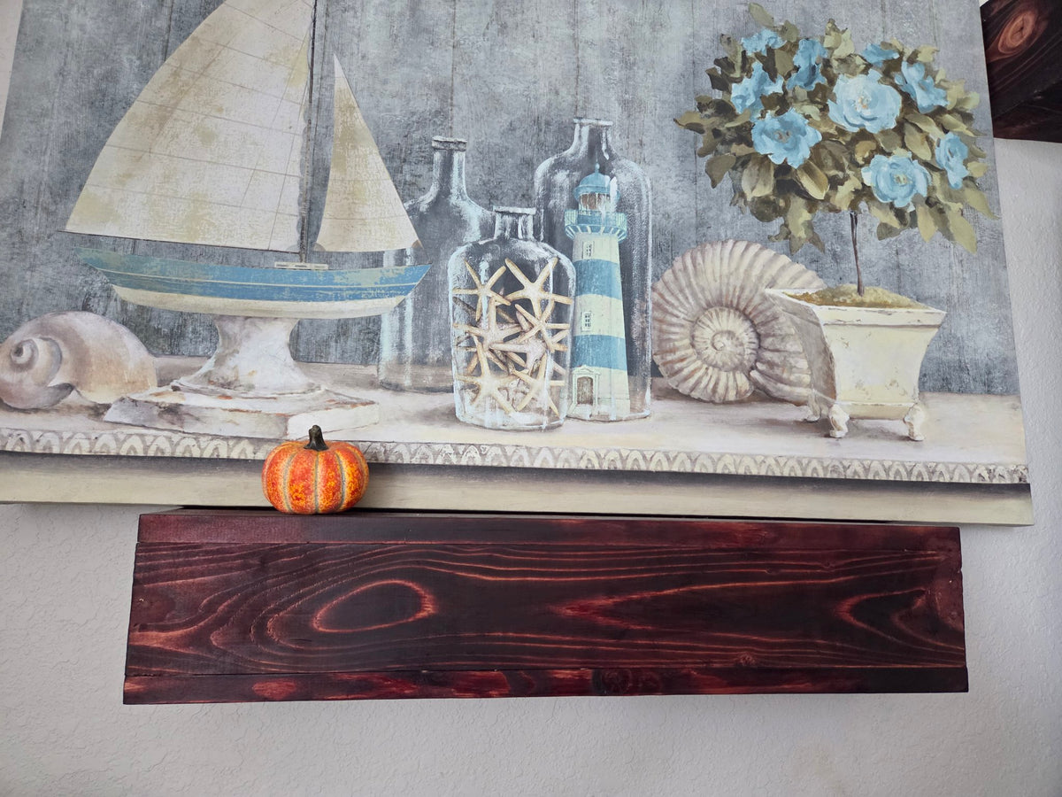 Dark-stained solid wood floating shelf mounted on a wall under artwork