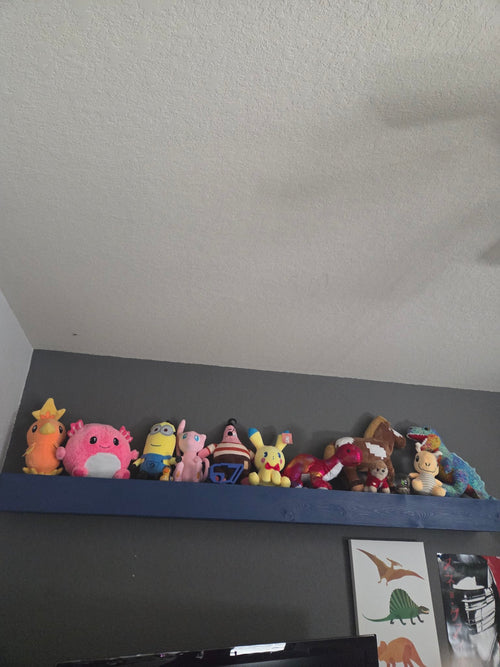 Long blue stained floating shelf displaying plush toys